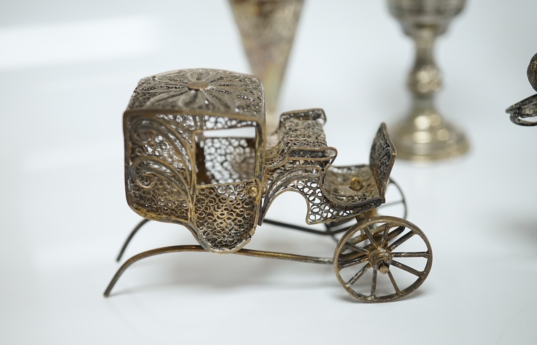 A small collection of miniature silver and white metal items including a cot by Saunders & Shepherd, Birmingham, 1896, 57mm, two filigree items, two Kiddush cups etc. Condition - poor to fair